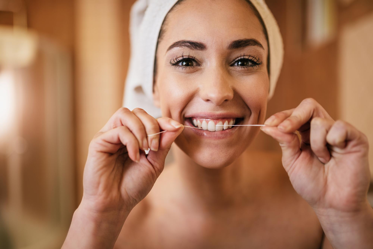 Mujer usando hilo dental como parte de la higiene bucal diaria para prevenir encías inflamadas